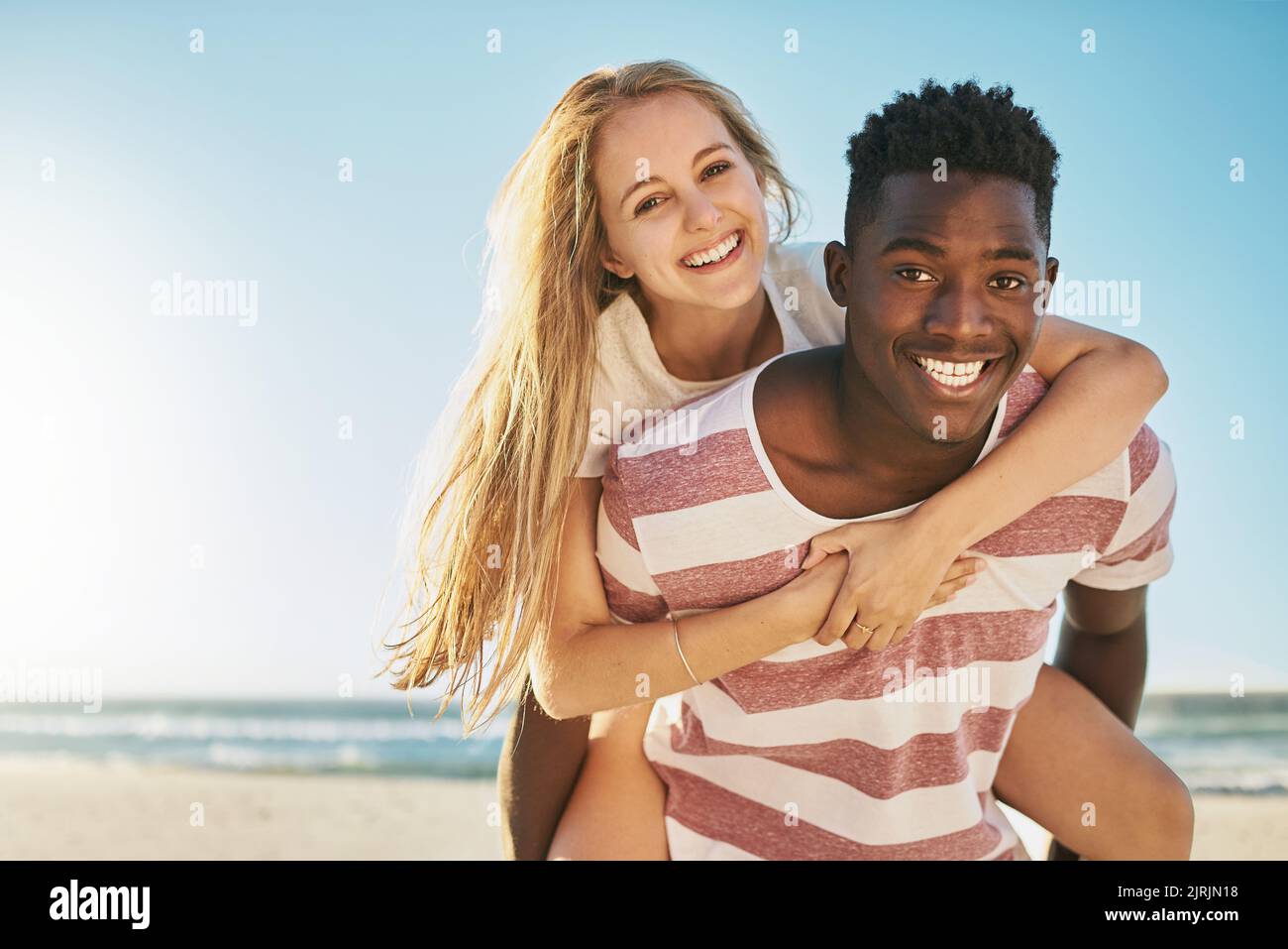 Nichts sagt Sommerromantik wie eine Huckepack-Fahrt. Ein glückliches junges Paar genießt eine Huckepack-Fahrt am Strand. Stockfoto