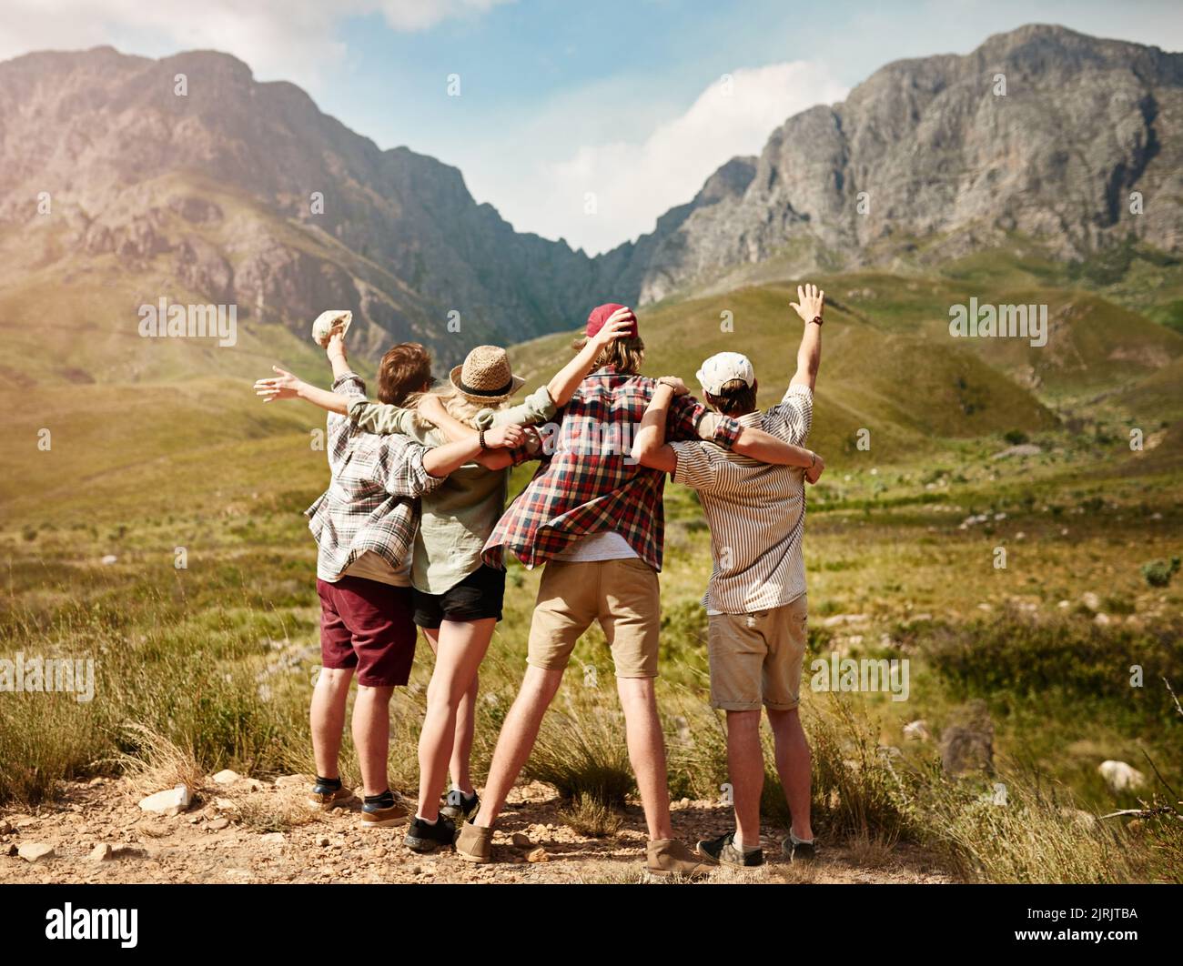 Die besten Jahre unseres Lebens. Rückansicht einer Gruppe von Freunden, die jubelnd die Aussicht auf die Berge in der Natur bewundern. Stockfoto