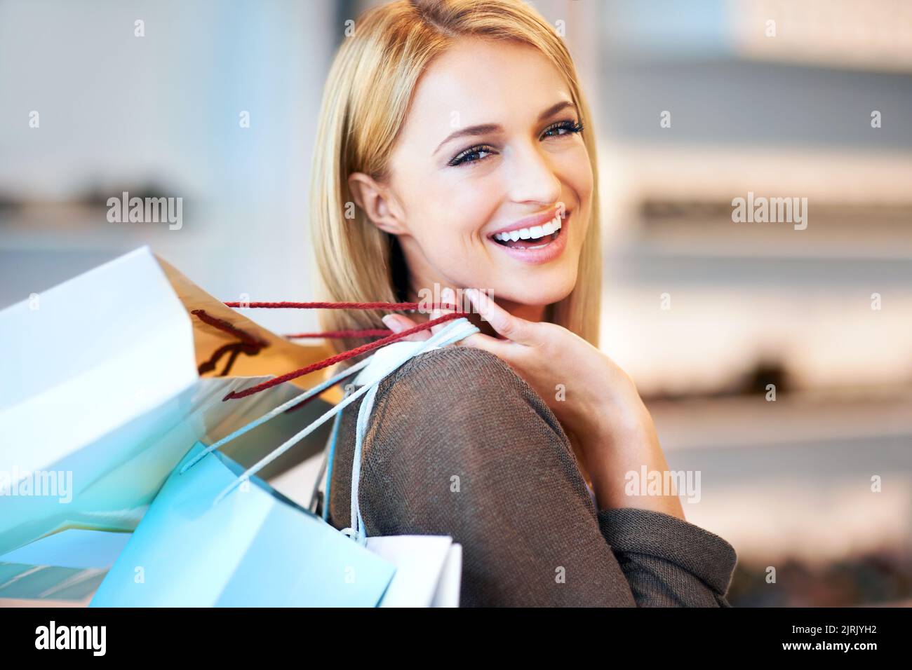Kunde, der mit einer Einkaufstasche im Einkaufszentrum herumläuft, in einer Designer-Modeboutique mit einem Lächeln und glücklich mit dem Verkauf im Einzelhandelsgeschäft. Porträt des Gesichts der reichen Frau Stockfoto
