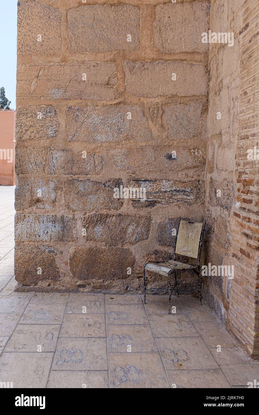 Alte, verlassene, leere Sitzbank in einer frischen Ecke im Schatten von Marrakesch, Marokko an einem sonnigen Tag im Stadtbild Stockfoto