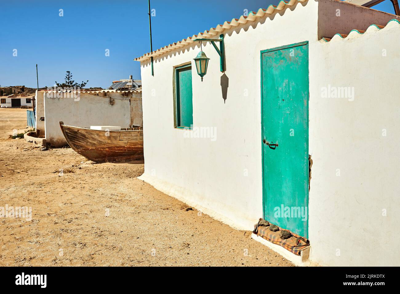 Alte Wohnhausfassaden mit Solarzellen auf Dächern gegen Sandstraße in Fuerteventura auf den Kanarischen Inseln Spanien Stockfoto