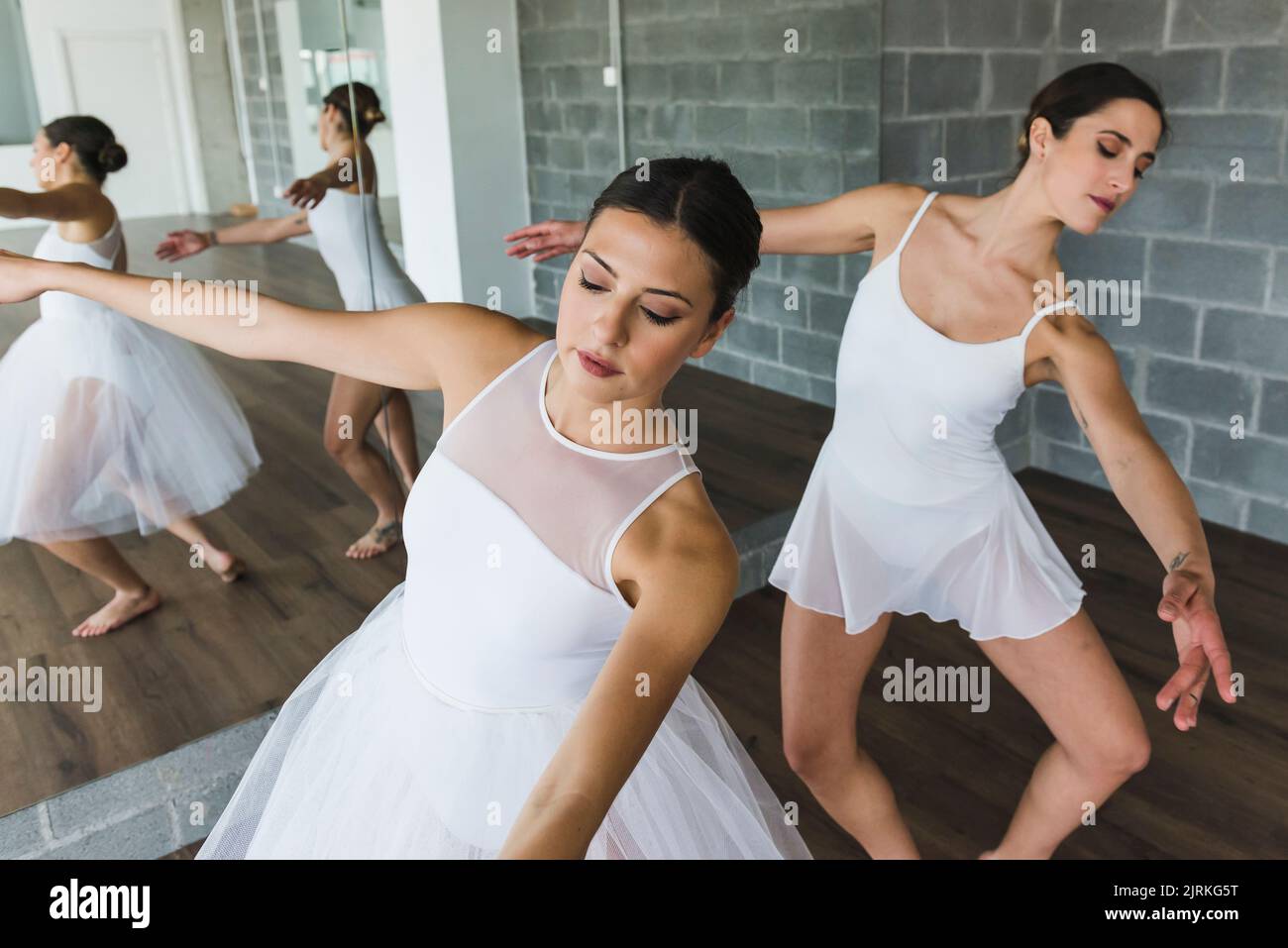 Zwei elegante junge Ballerinas tanzen synchron neben einem Spiegel in einem Tanzstudio Stockfoto