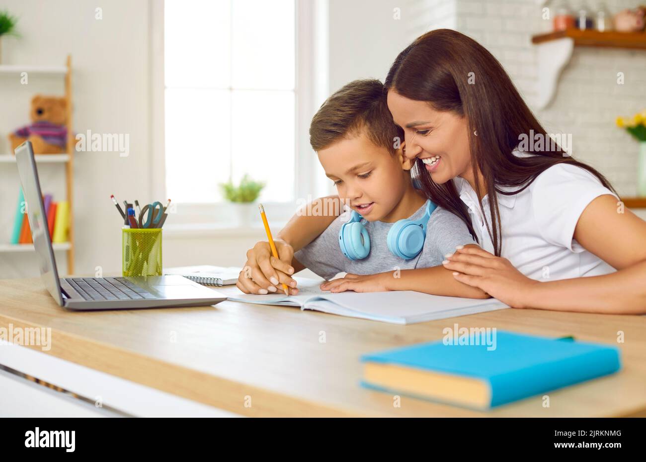 Die freundliche, fürsorgliche junge Mutter lehrt ihren Vorschulkinder-Sohn, zu Hause Briefe zu schreiben. Stockfoto