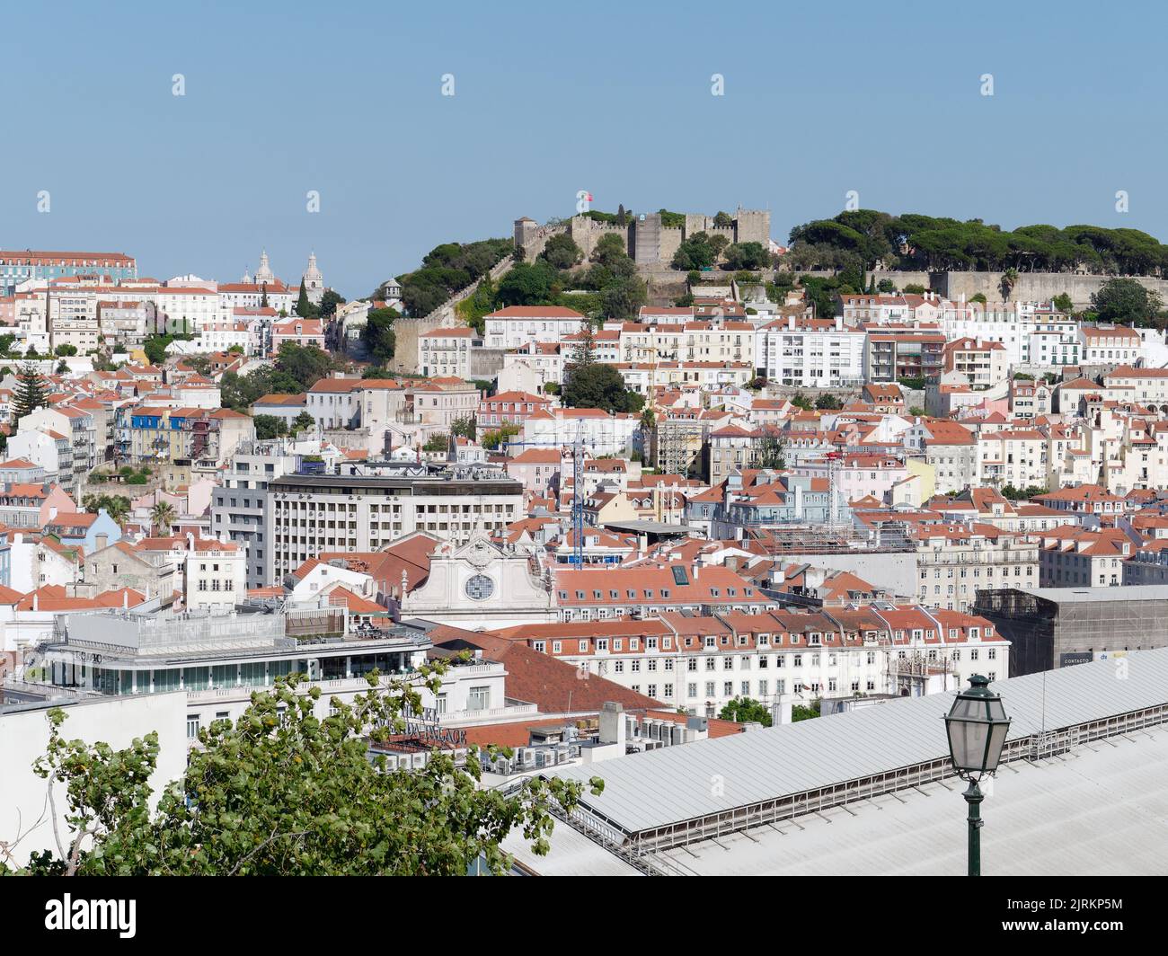Blick vom Aussichtspunkt (Miradouro) São pedro de Alcântara in Lissabon, Portugal an einem Sommerabend über den Dächern der Stadt. Schloss St. Georges dahinter. Stockfoto