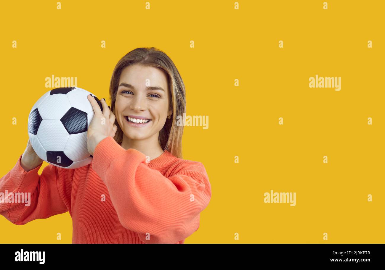 Lächelnde junge Frau mit klassischem weißen und schwarzen Fußballball in den Händen auf Bannerhintergrund. Stockfoto
