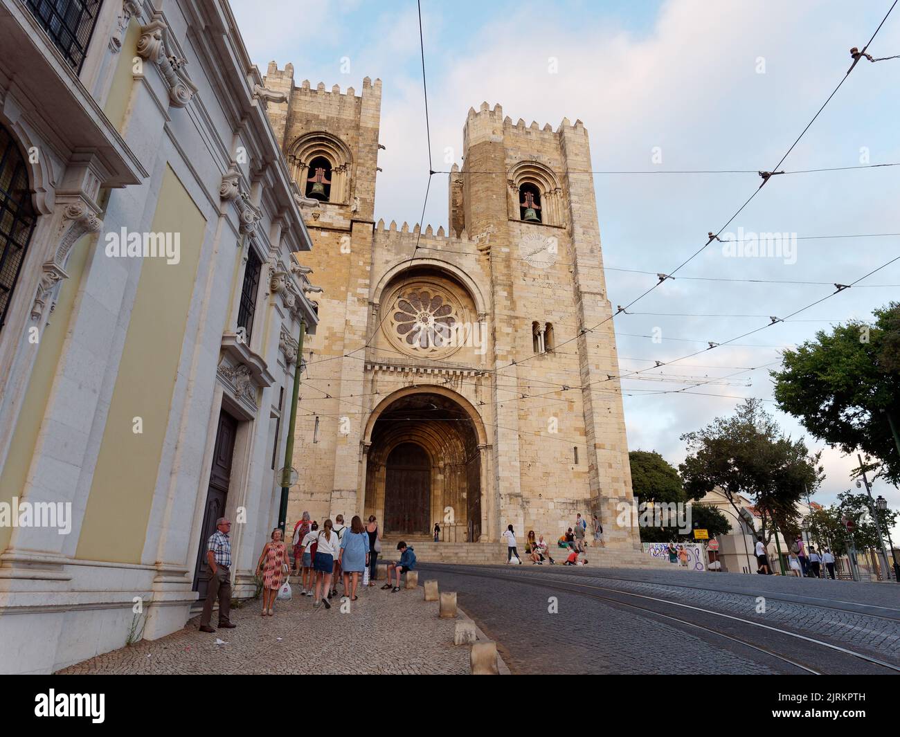 Kathedrale Saint Mary Major alias Lissabon Kathedrale alias Sé de Lisboa. Touristen laufen auf der Straße mit den Straßenbahnlinien. Stockfoto