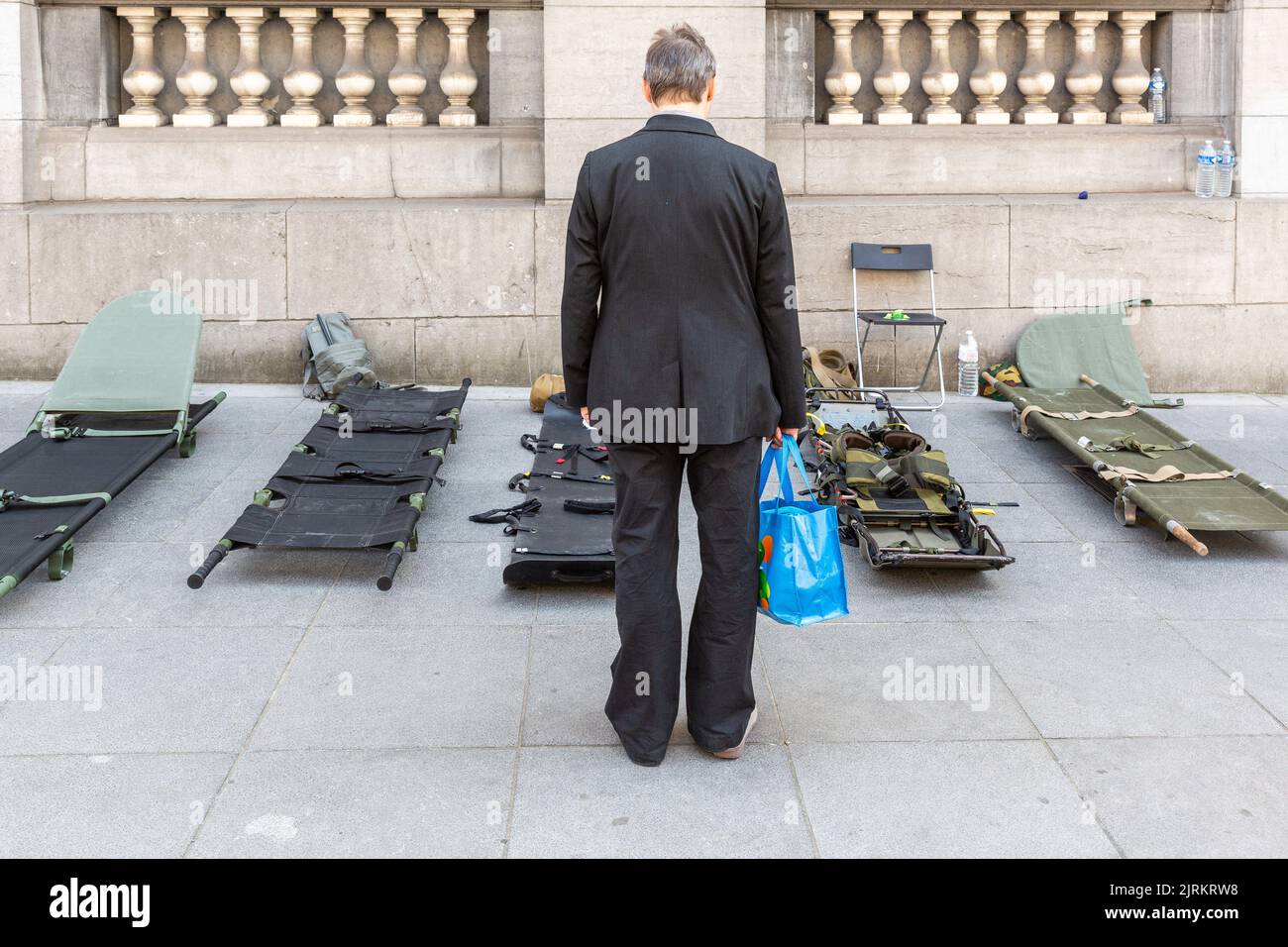 Mann, der eine blaue Tasche trägt und einige Bahren vom Roten Kreuz der Armee ansieht. Stockfoto