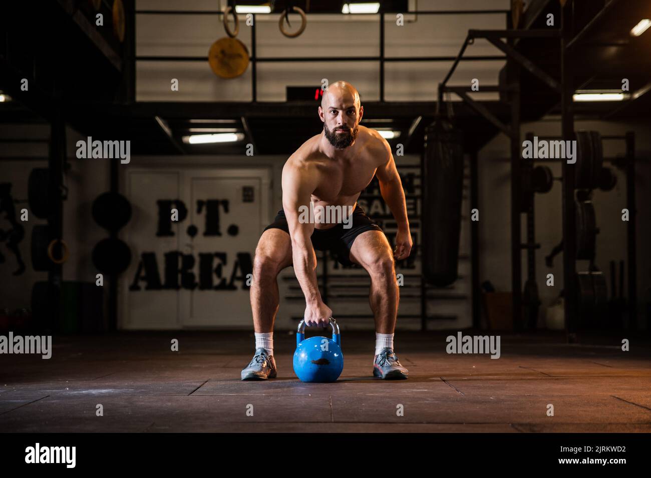 Kraftvoller Sportmann, der in einem Fitnessstudio einen schweren Kessel hochhebt, Bodybuilding-Übung. Bodybuilding-Workout in einem Fitnessstudio. Stockfoto