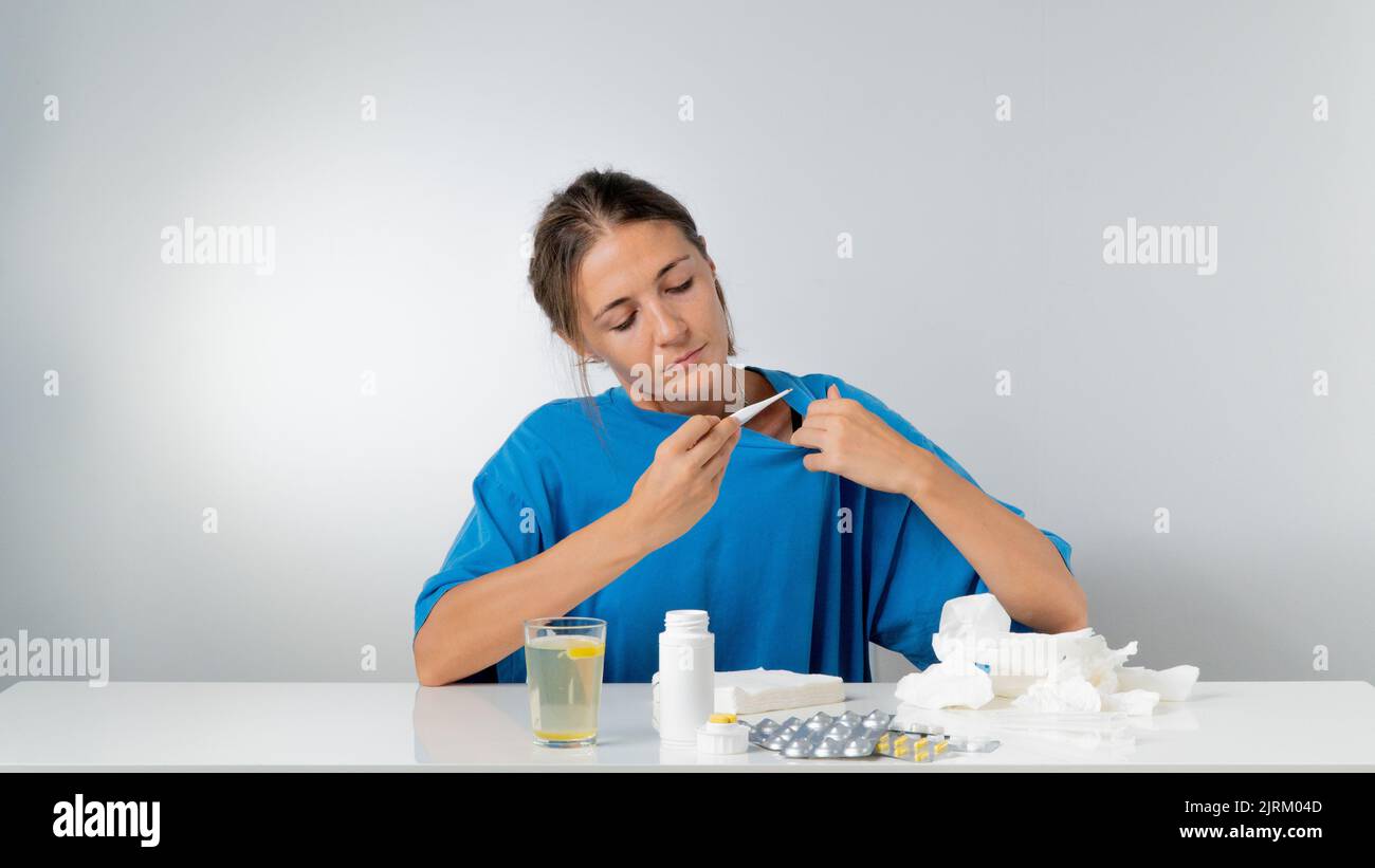 Eine Frau nimmt ihre Temperatur während einer Grippekrankheit - Behandlung Stockfoto