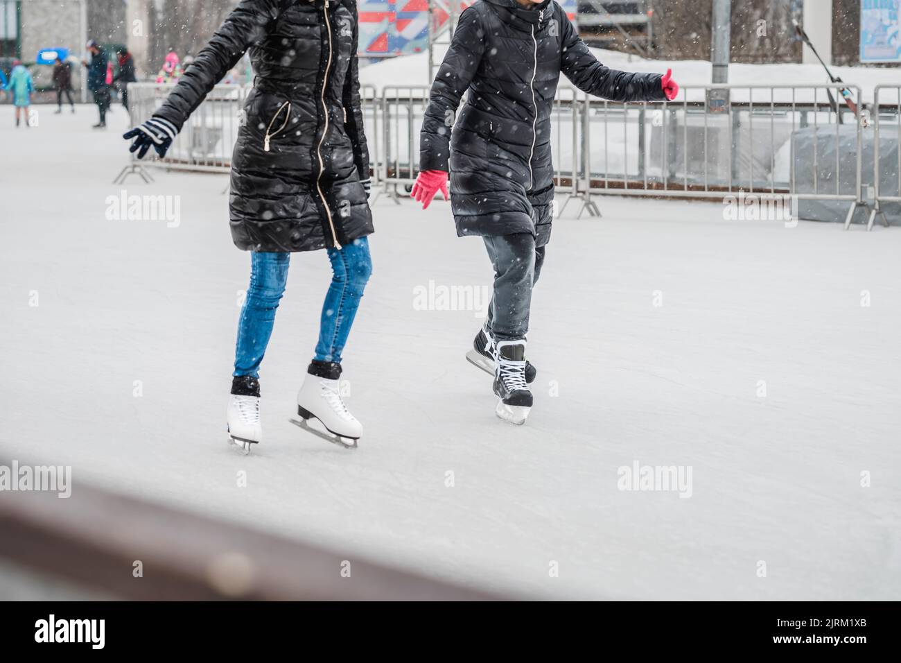 Zwei abstrakte Mädchen Schlittschuhlaufen auf einer Eisbahn im Stadtpark. Gesunde Outdoor-Aktivitäten im Winter Stockfoto