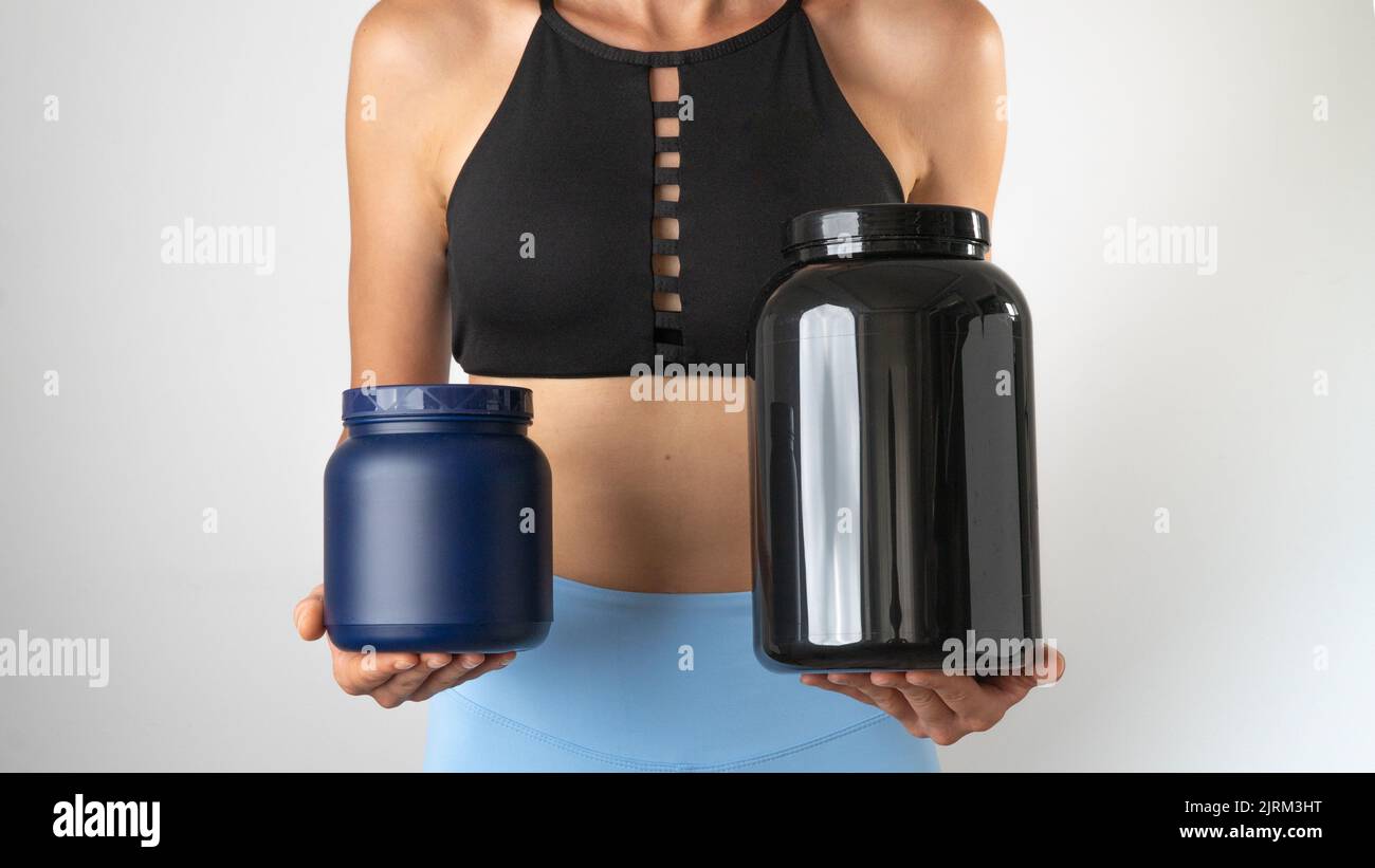 Sportliche schlanke Frau mit Dosen Protein und Sportzusätzen für ein effektives Workout im Fitnessstudio Stockfoto