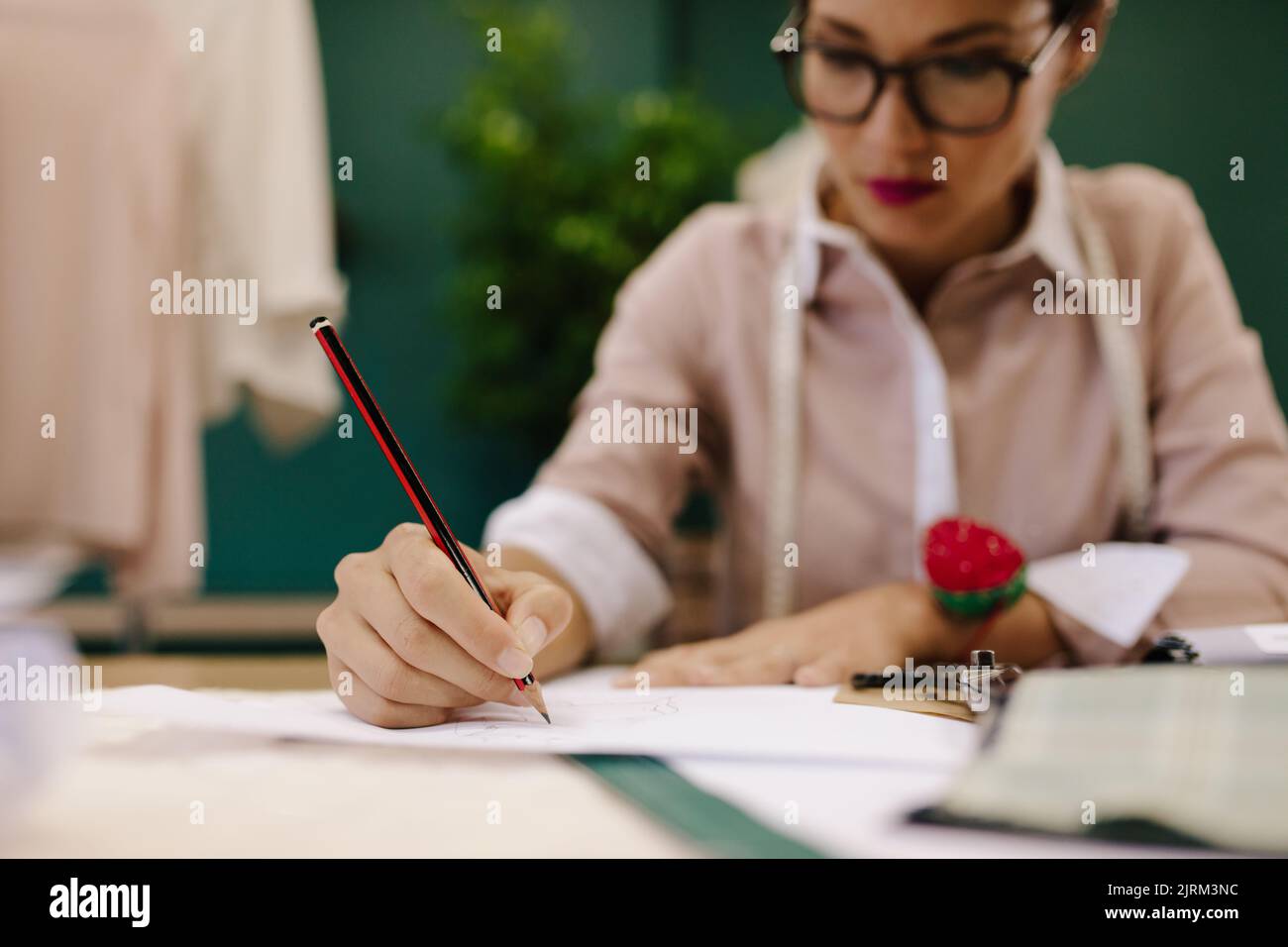 Weibliche Hand zeichnet Skizzen auf Papier. Frau Schneiderin macht Kleid Design Skizzen im Modestudio. Stockfoto