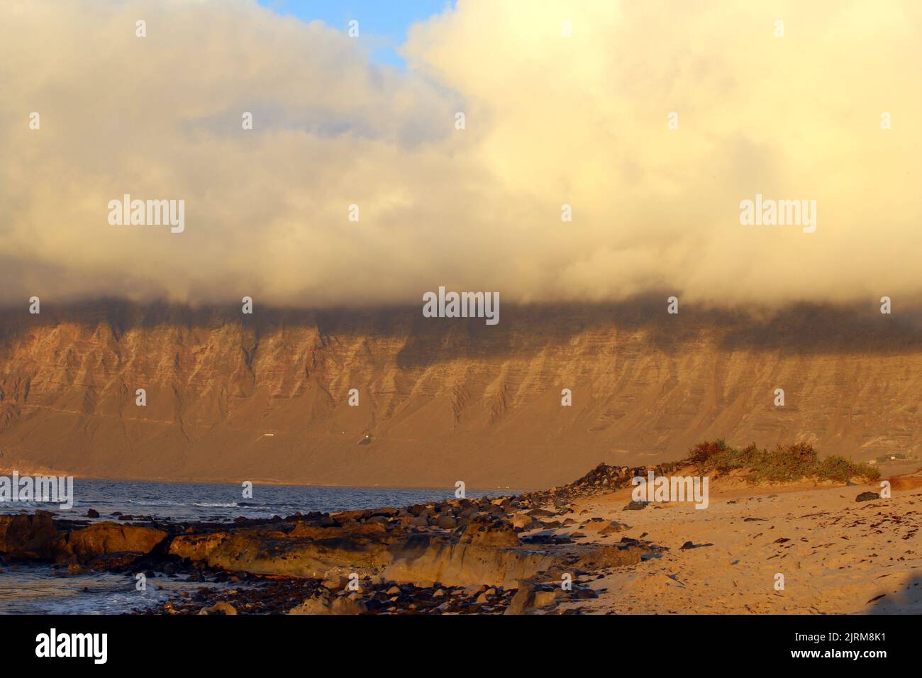 Blick auf den Risco de Famara vom Strand San Juan bei Sonnenuntergang Stockfoto