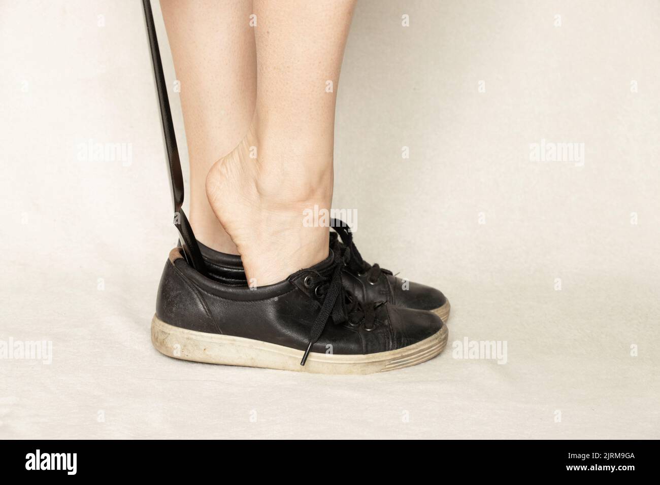 Mädchenschuhe schwarze Sneakers mit einem Schuhhorn auf weißem Hintergrund, Schuhe, schwarze Damen-Sneakers Stockfoto