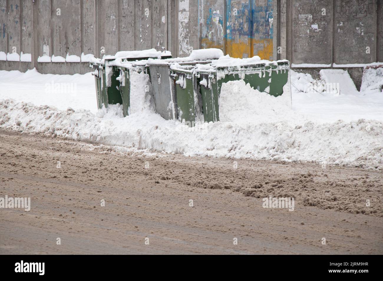Mülleimer im Schnee in der Nähe des Zauns auf der Straße, Müllabfuhr, Mülleimer im Winter Stockfoto