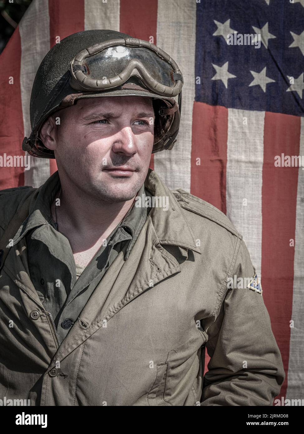 Eine vertikale Aufnahme eines Soldaten aus dem Jahr WW2, der gegen die Flagge der USA schaut Stockfoto