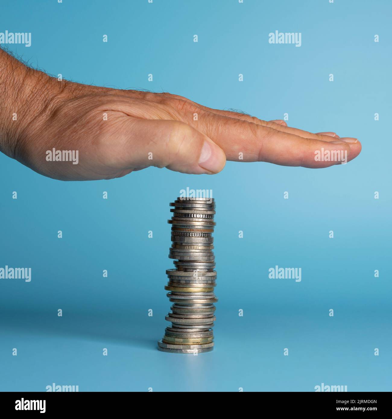 Eine Hand über einen schwebenden Stapel von Münzen. Im Konzept des Schutzes vor dem Verlust des Währungswertes als Folge der Inflation Stockfoto