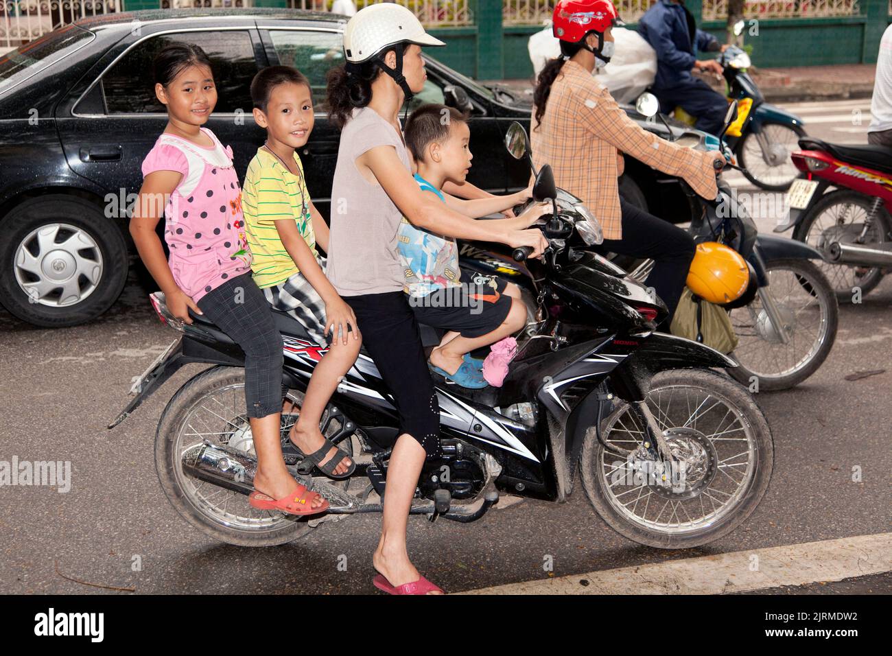 Mutter und drei Kinder auf dem Motorrad im Straßenverkehr, Hai Phong, Vietnam Stockfoto