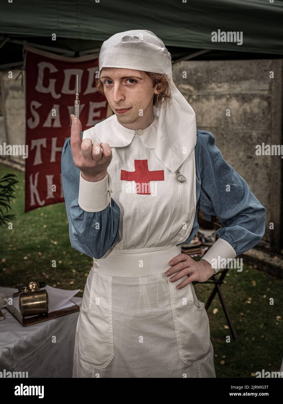 Eine vertikale Aufnahme einer Reenactor-Krankenschwester im Jahr WW2 mit einer Spritze. Historische Reenactment Stockfoto