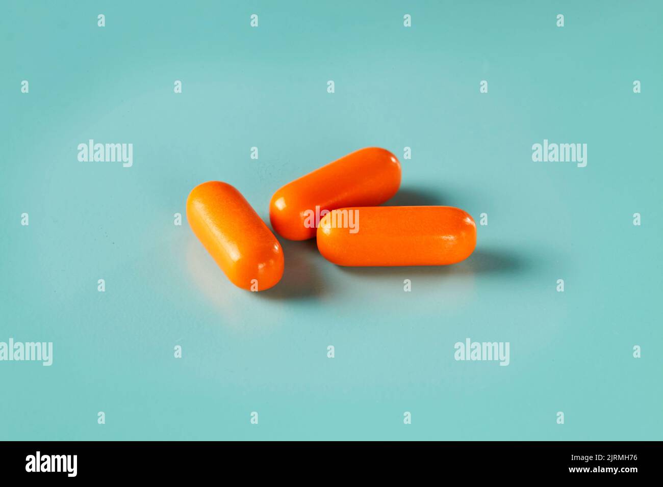 Drei orangefarbene Kapseln auf cyanfarbenem Hintergrund Stockfoto