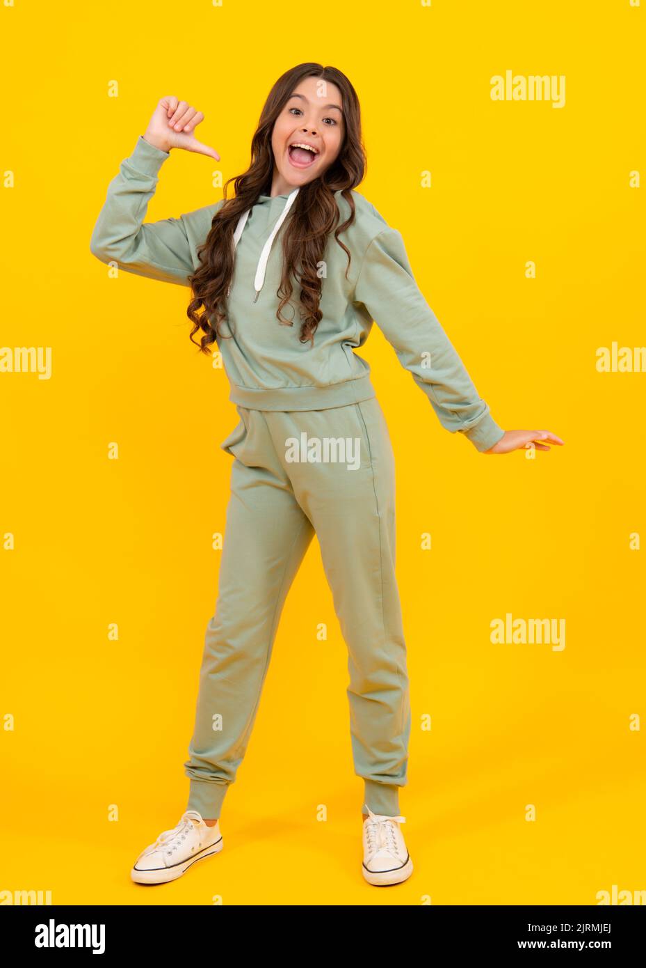 Erstaunt teen Mädchen. Niedliches Teenager-Mädchen in einem lila lässigen Sportanzug Hoodie und Hosen und weißen Sneakers posiert auf weißem Hintergrund. Mock-up für den Druck Stockfoto