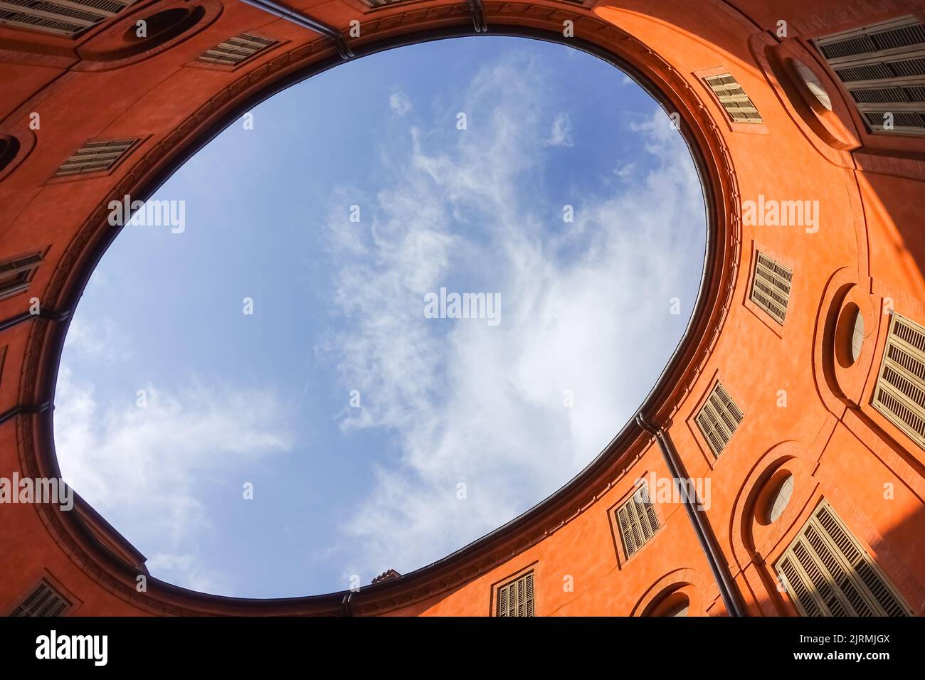 Innenhof des ovalen orange kommunalen Theatergebäudes in Ferrara, Italien mit Blick auf den Himmel für eine gewerbliche Immobilien-Management-Hintergrund Stockfoto