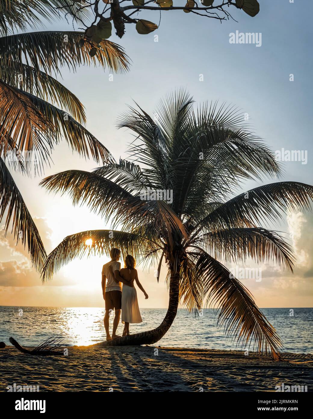 Romantisches junges Paar zusammen am schönen exotischen tropischen Strand unter Palmen bei Sonnenuntergang. Foto herunterladen Stockfoto