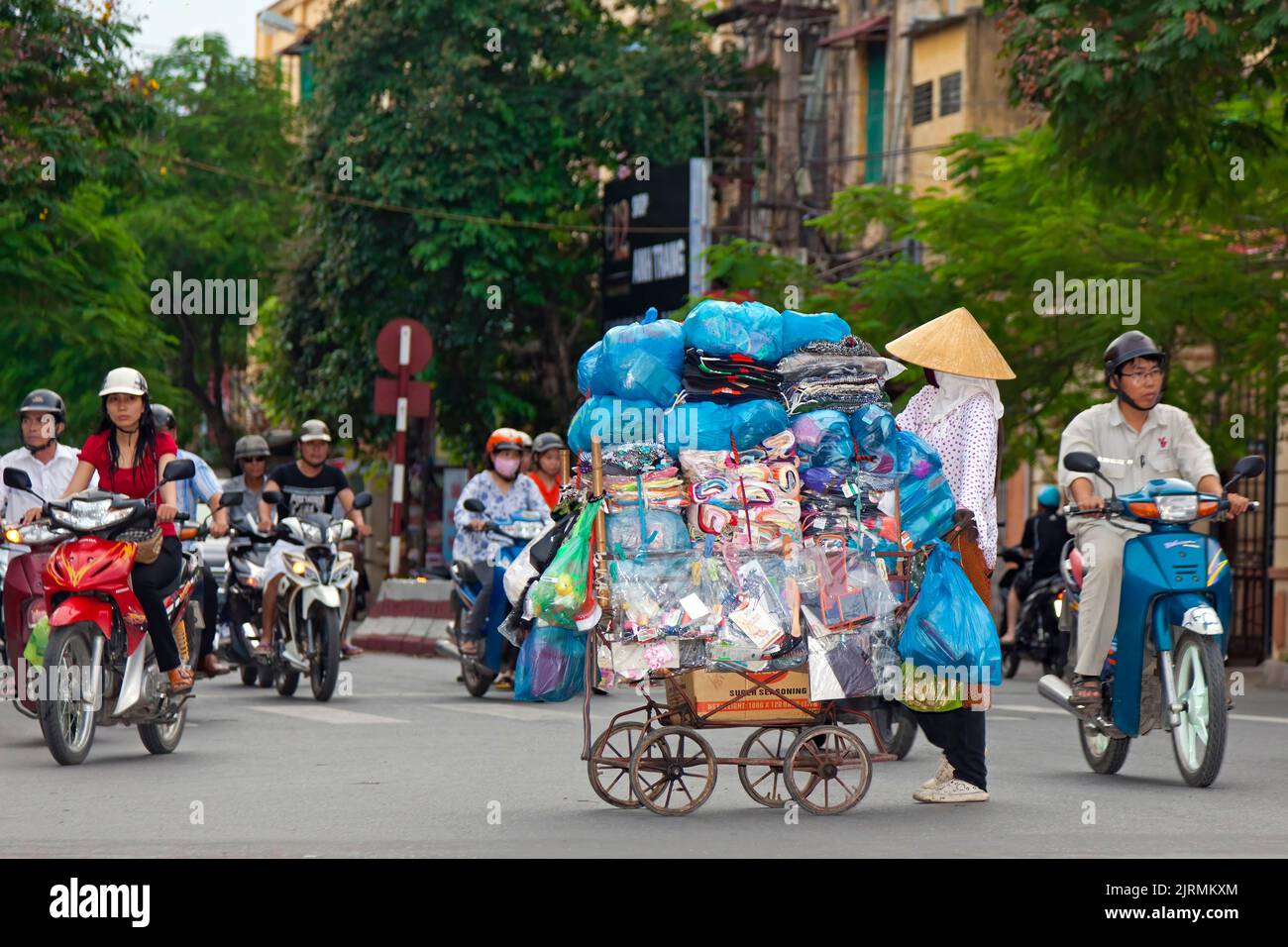 Vietnamesischer Straßenhändler mit Wagen unter Motorrädern an der Verkehrsampel, Hai Phong, Vietnam Stockfoto