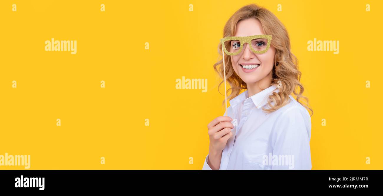 Mädchen mit lustigen Party-Brille. Lächelnde Frau mit lustigen Party-Brille auf gelbem Hintergrund. Frau isoliert Gesicht Porträt, Banner mit Nachbau Kopie Stockfoto