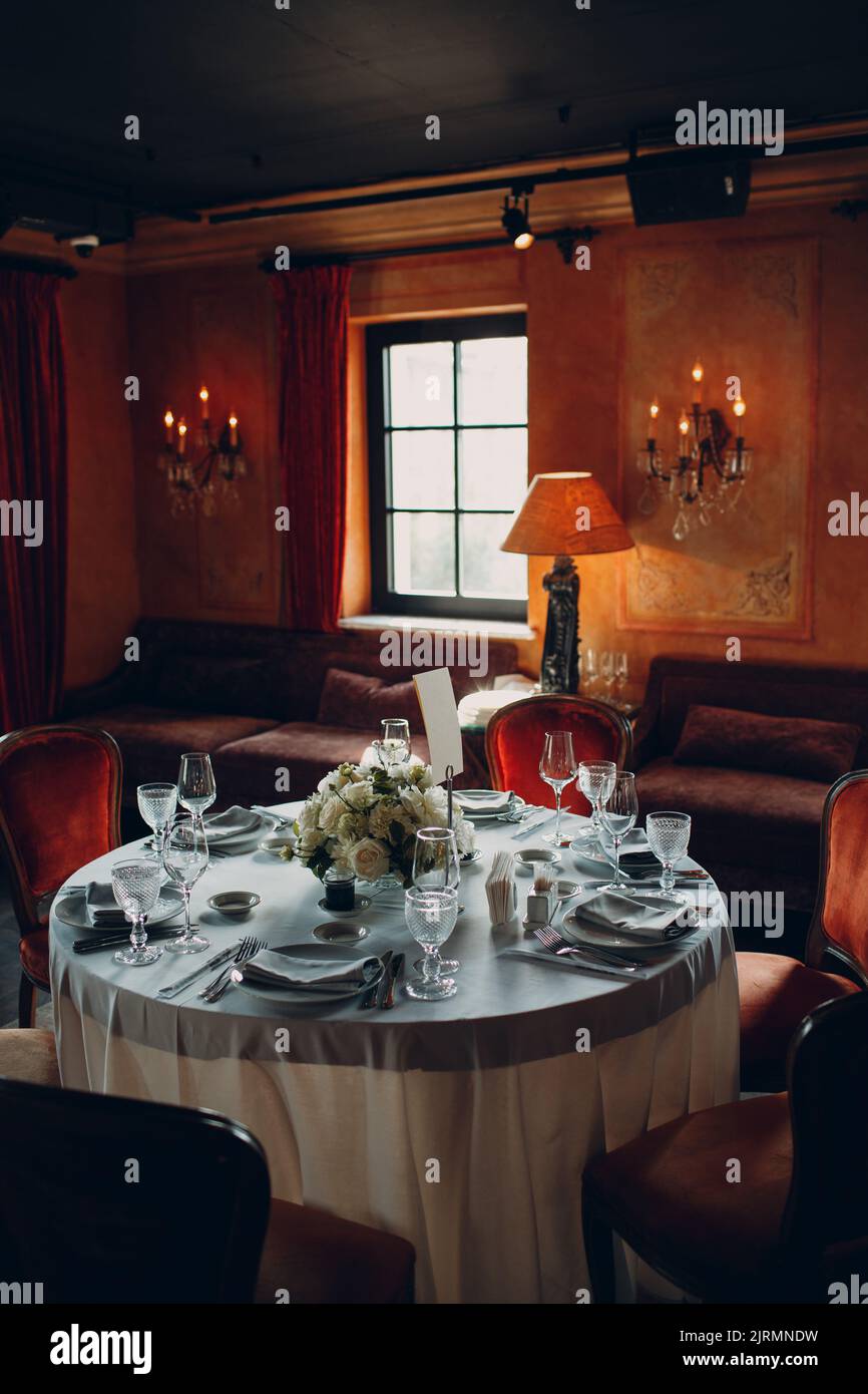 Runde Tische im Restaurant mit weißen Tischdecken und weißen Blumensträußen. Stockfoto