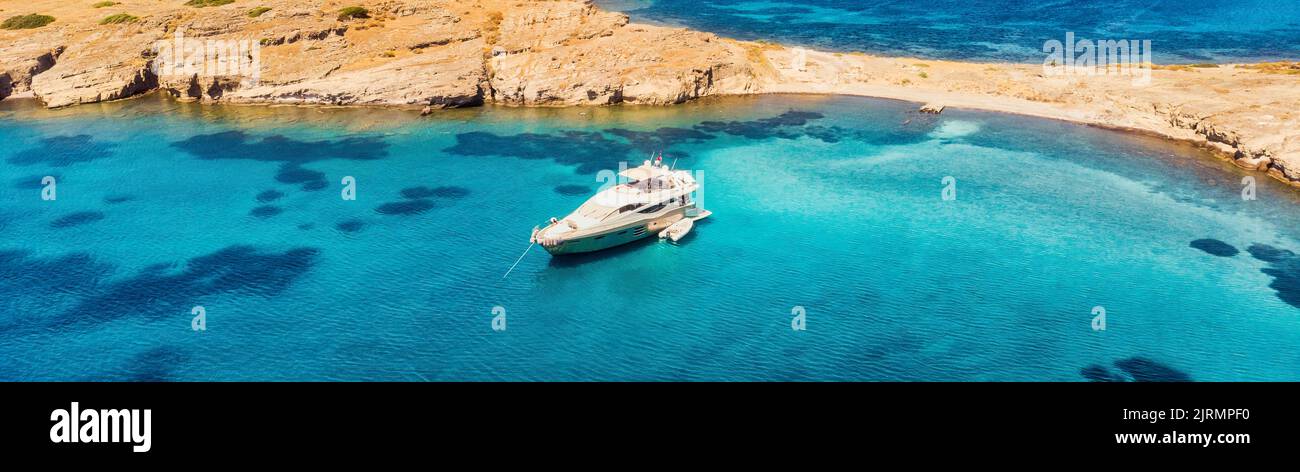Blick von oben, atemberaubende Luftaufnahme einer Bucht mit Boot, Luxus-Yacht, die auf einem türkisfarbenen, klaren Wasser segelt. Stockfoto