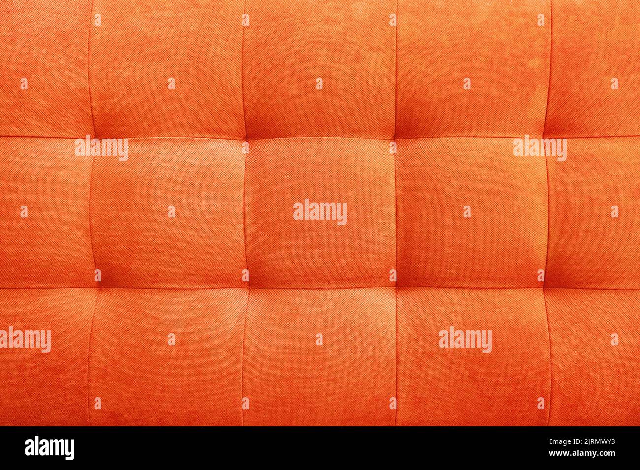 Orangefarbener Veloursleder-Hintergrund für die Wand im Raum. Interior Design, Kopfteile aus Möbelstoff, Möbelpolsterung. Klassischer Checkereklassiker Stockfoto