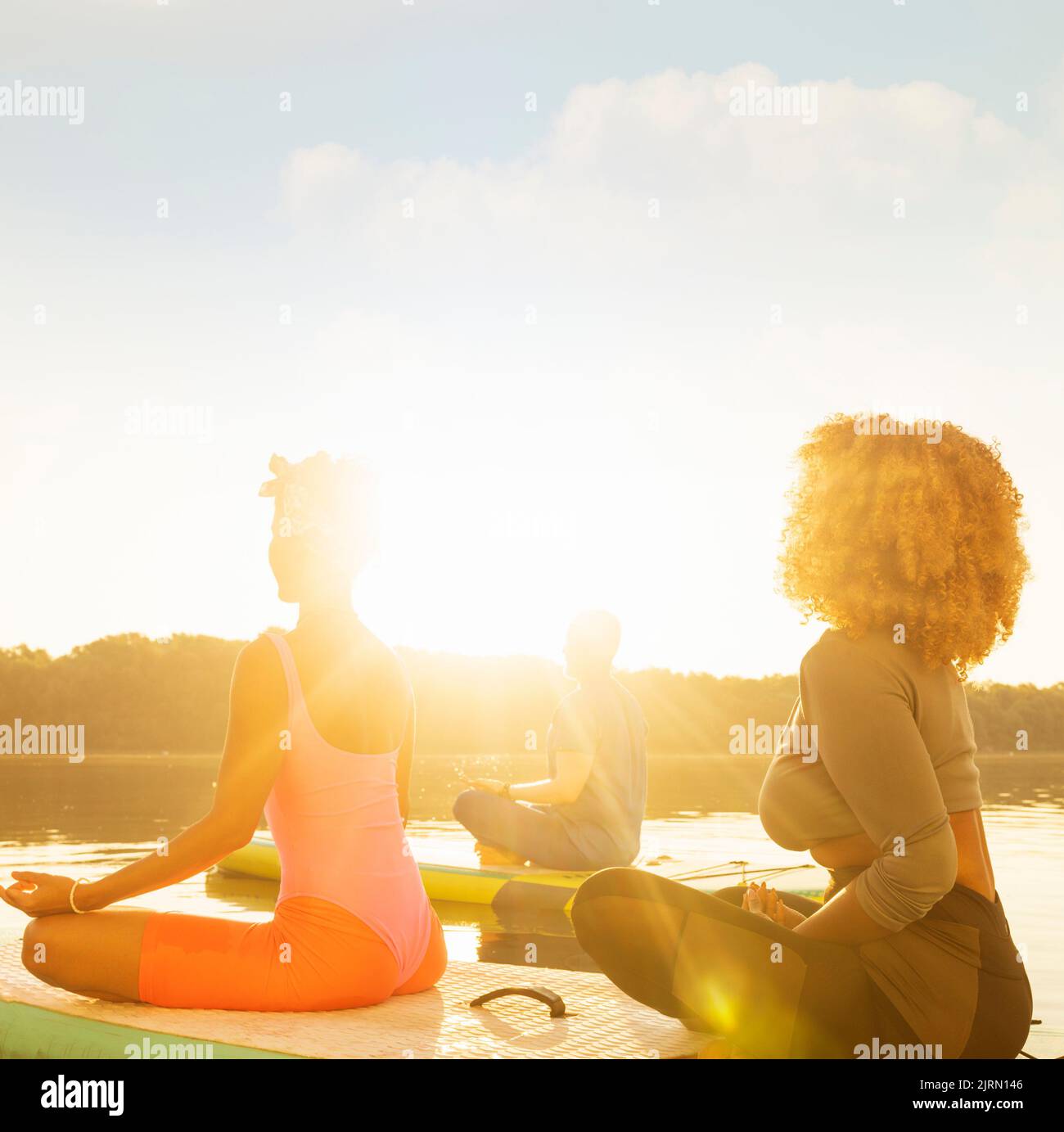 Eine Gruppe von drei Personen meditierte auf SUP-Boards und entspannte sich am Morgen Stockfoto