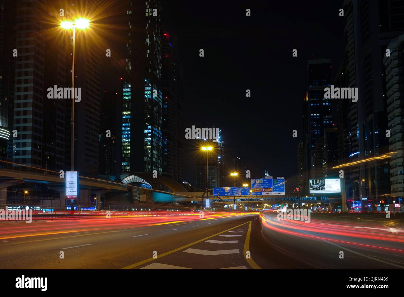 Hohe Gebäude und schnelle Autos entlang der Sheikh Zayed Road, der längsten Autobahn in Dubai und den Vereinigten Arabischen Emiraten. Nachts Stadtbild im Freien. Stockfoto