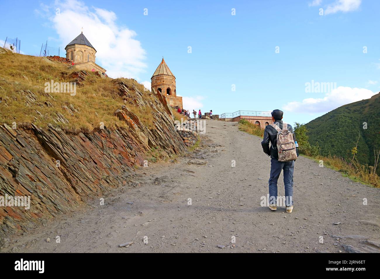 Besucher steigen zur mittelalterlichen Dreifaltigkeitskirche Gergeti, einer ikonischen Desination der Stadt Stepantsminda, Kazbegi, Georgien Stockfoto