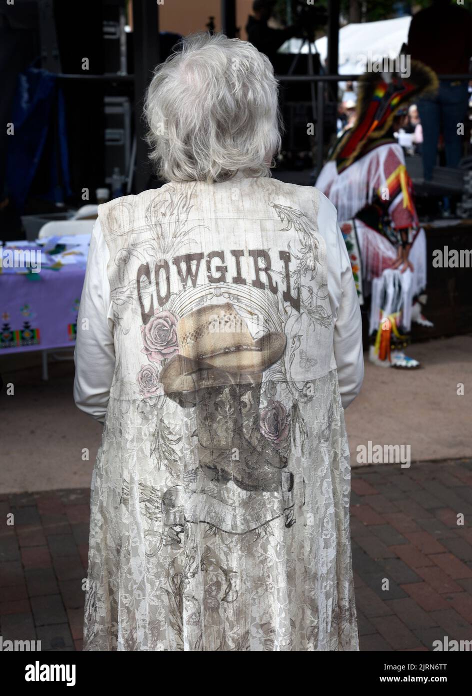 Eine ältere Frau trägt ein Kleid mit Cowgirl-Bildern auf dem Santa Fe Indian Market in Santa Fe, New Mexico. Stockfoto