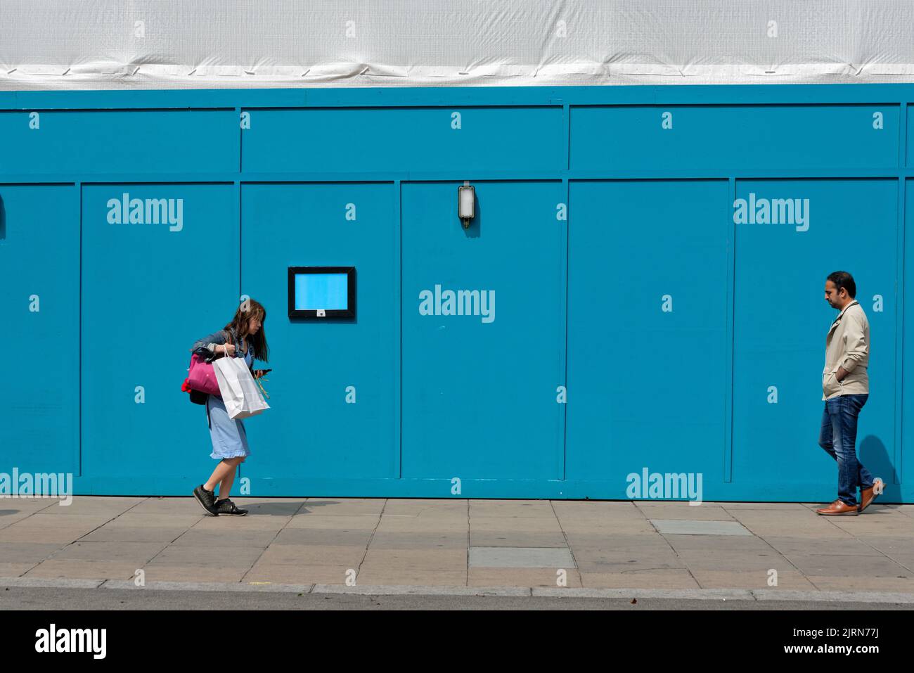 Menschen, die an einem blauen Gebäude vorbeikommen, das ein abstraktes Bild auf der Londoner Oxford Street in England erstellt Stockfoto