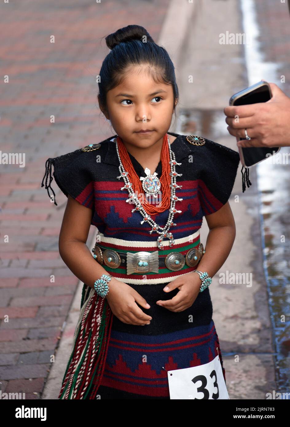 Ein junges Mädchen aus der amerikanischen Ureinwohner (Navajo) wartet auf ihre Teilnahme am Native American Clothing Contest auf dem Santa Fe Indian Market in New Mexico. Stockfoto