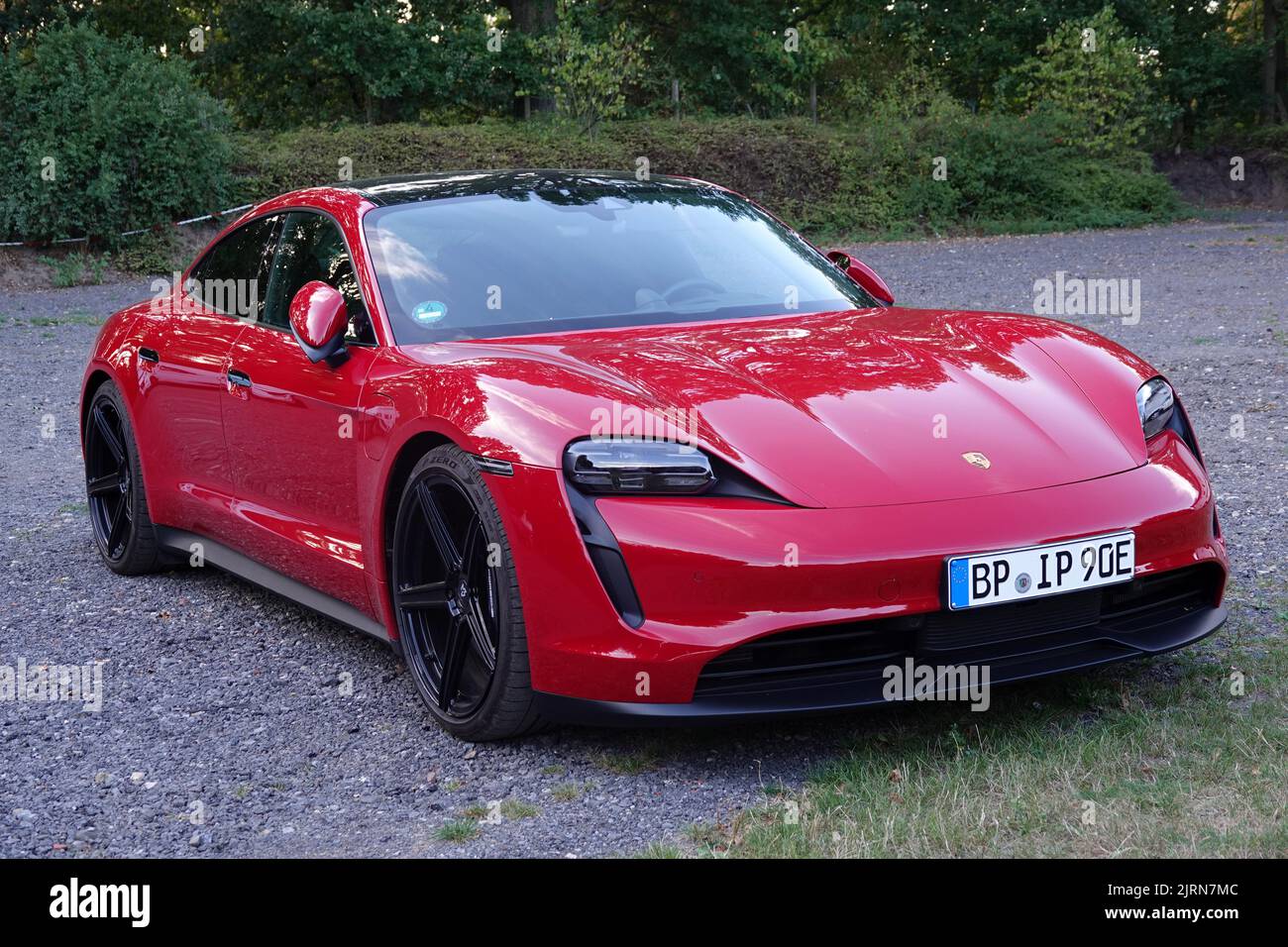 Rheine, NRW, Deutschland - August 24 2022 Ein roter Porsche Taycan parkte auf Schotter. Dies ist eine elektrische Limousine und die erste serienmäßig produzierte elektrische Ca Stockfoto