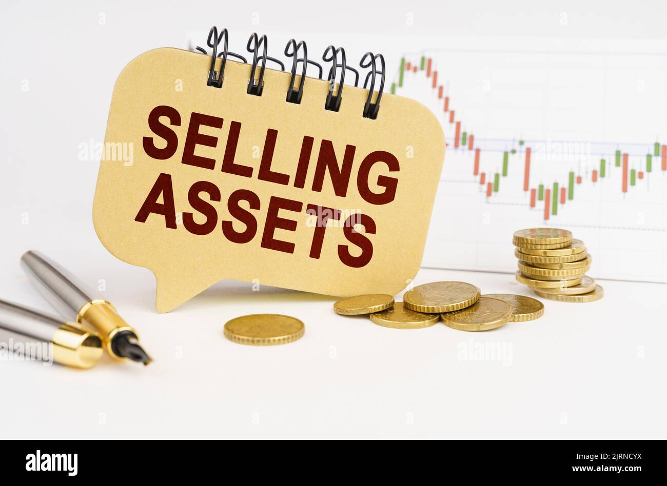 Geschäftskonzept. Auf dem Tisch befinden sich Münzen, ein Stift, eine Grafik und ein Schild mit der Aufschrift - Verkaufsvermögen Stockfoto