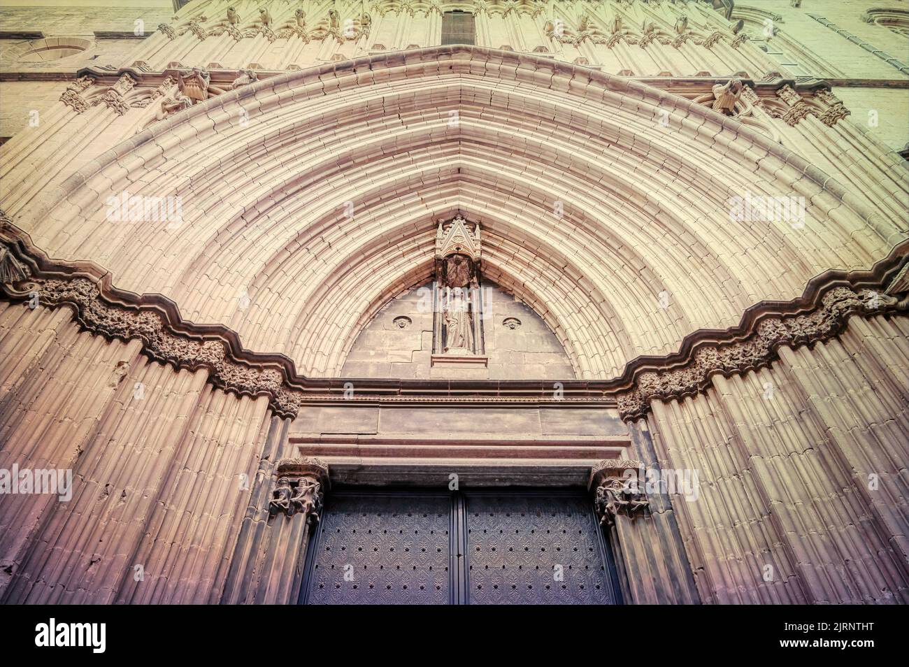 Niedriger Winkel Ansicht einer mittelalterlichen Tür. Der Eingang des Gebäudes ist mit mehreren Bögen in der Steinmauer verziert. Stockfoto