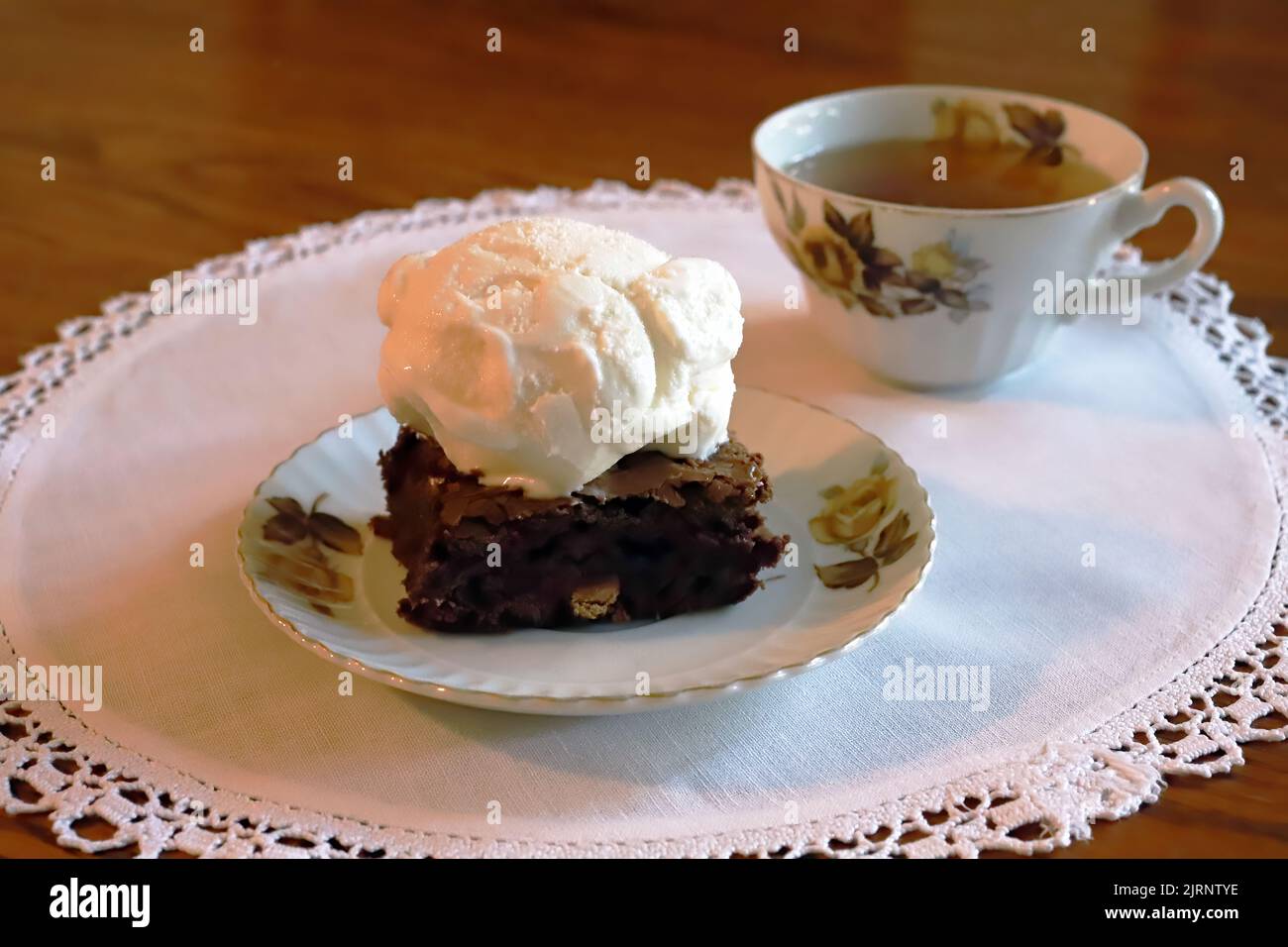 Köstliches Dessert mit Schokoladenbrownie und Eis mit einer Tasse Tee in porzellan. Stockfoto