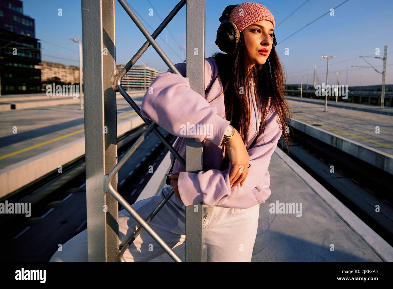 Ein Teenager-Mädchen lehnt sich am Bahnhof an die Metallkonstruktion und genießt die Musik. Stockfoto