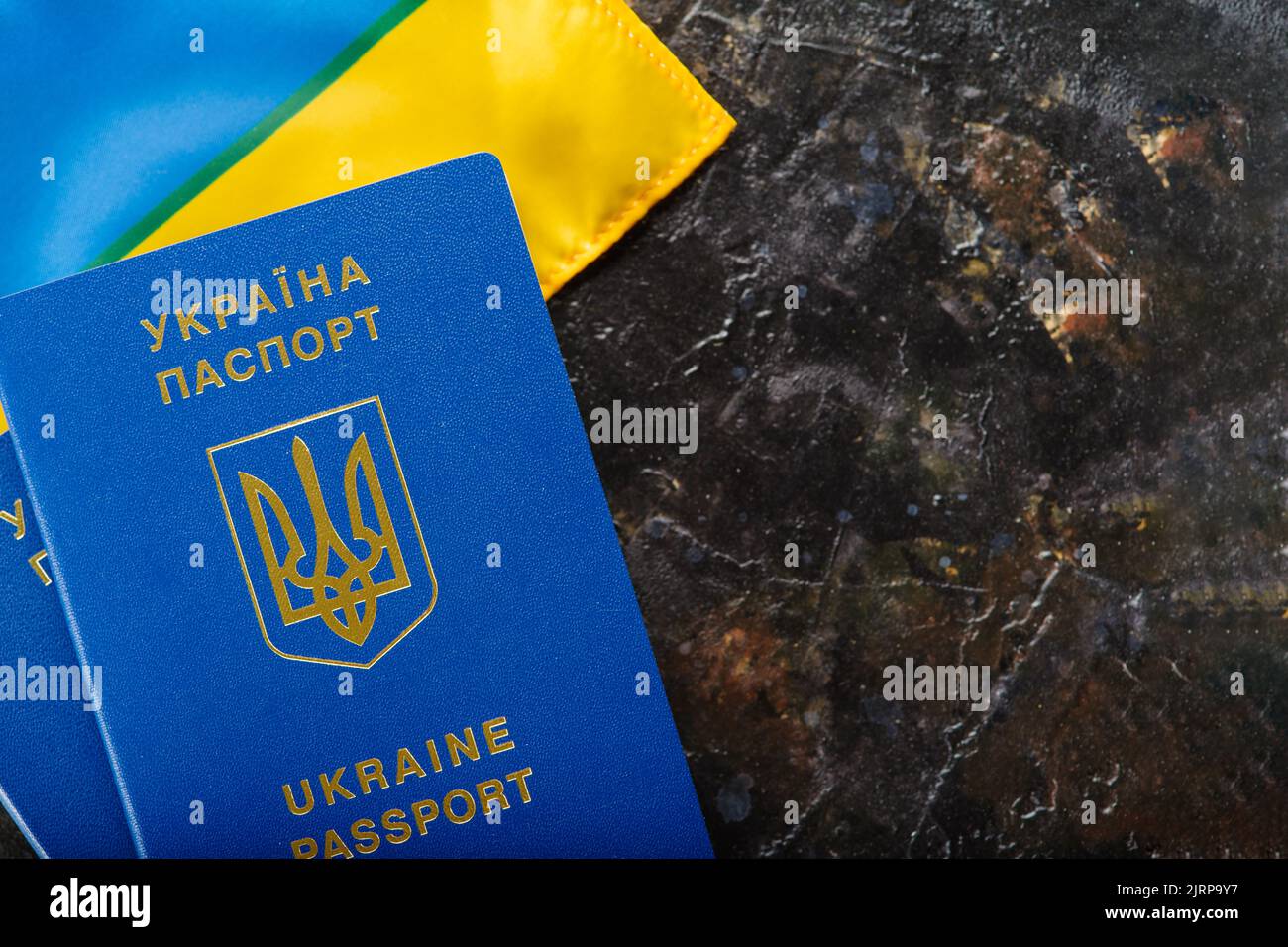 Ukrainischer biometrischer Pass und ukrainische Flagge auf dunklem Hintergrund. Emigration, Reisen, Tourismus, Flucht aus dem Krieg in der Ukraine, Identifikation. Der Stockfoto