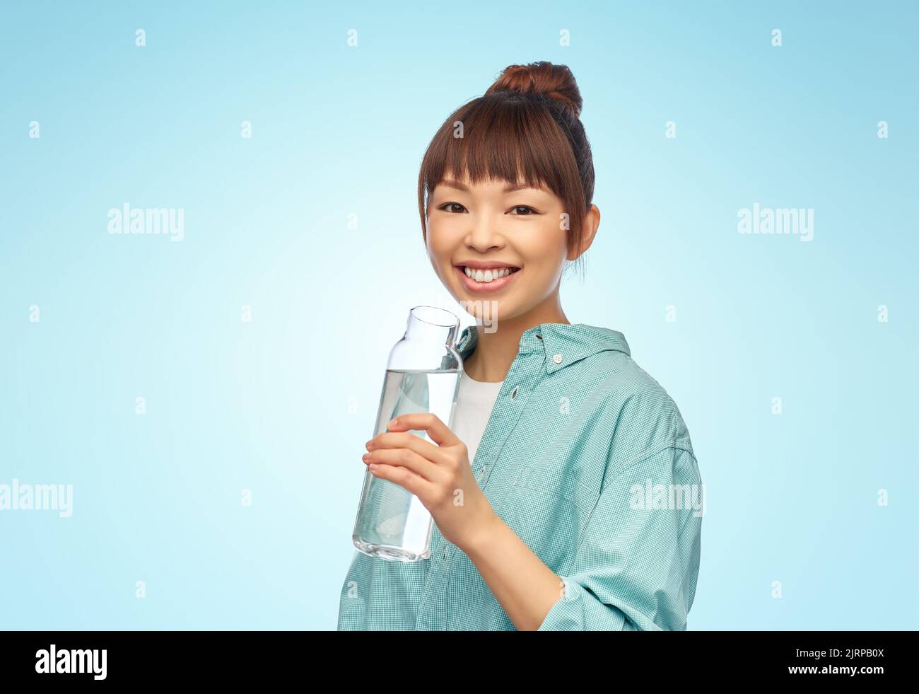 Glückliche asiatische Frau hält Glasflasche mit Wasser Stockfoto