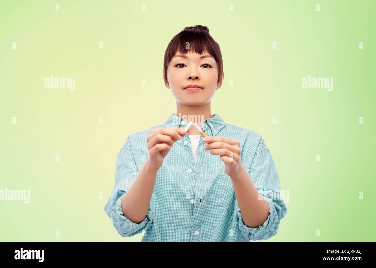 asiatische Frau bremst Zigarette über grün Stockfoto