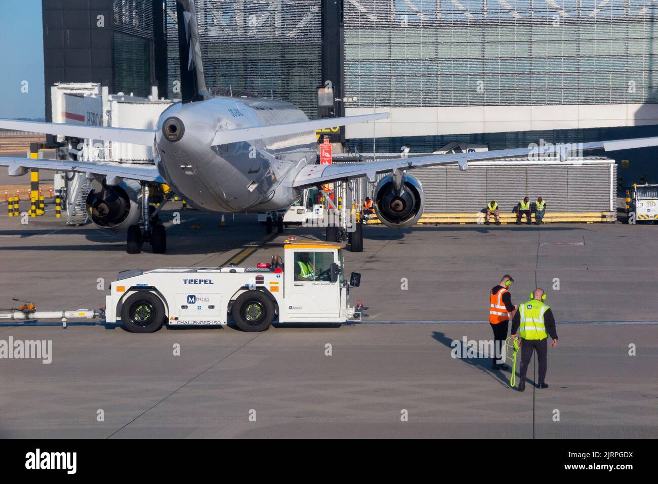 Mitarbeiter der Bodencrew mit Flughafenunterstützung, einem Fahrzeug mit Abschleppausrüstung und einem stationären geparkten Flugzeug/Flugzeug/Flugzeug/Flugzeug am LHR London Heathrow Airport. VEREINIGTES KÖNIGREICH. (131) Stockfoto