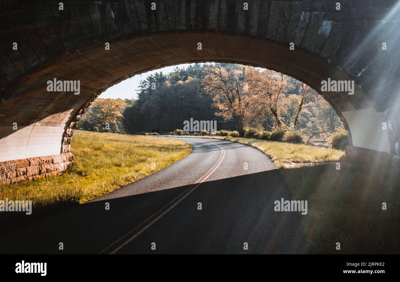 Der Blue Ridge Parkway schlängelt sich unter einer Steinbogenbrücke in Virginia Stockfoto