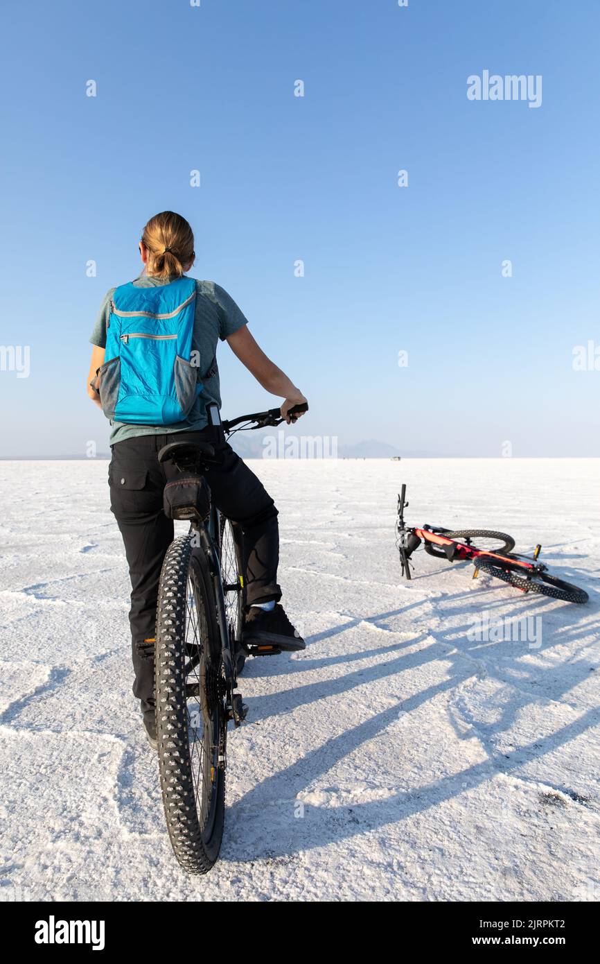 Frau, die auf Bonneville Salt Flats in Utah ein Fahrrad mit Rucksack fährt Stockfoto