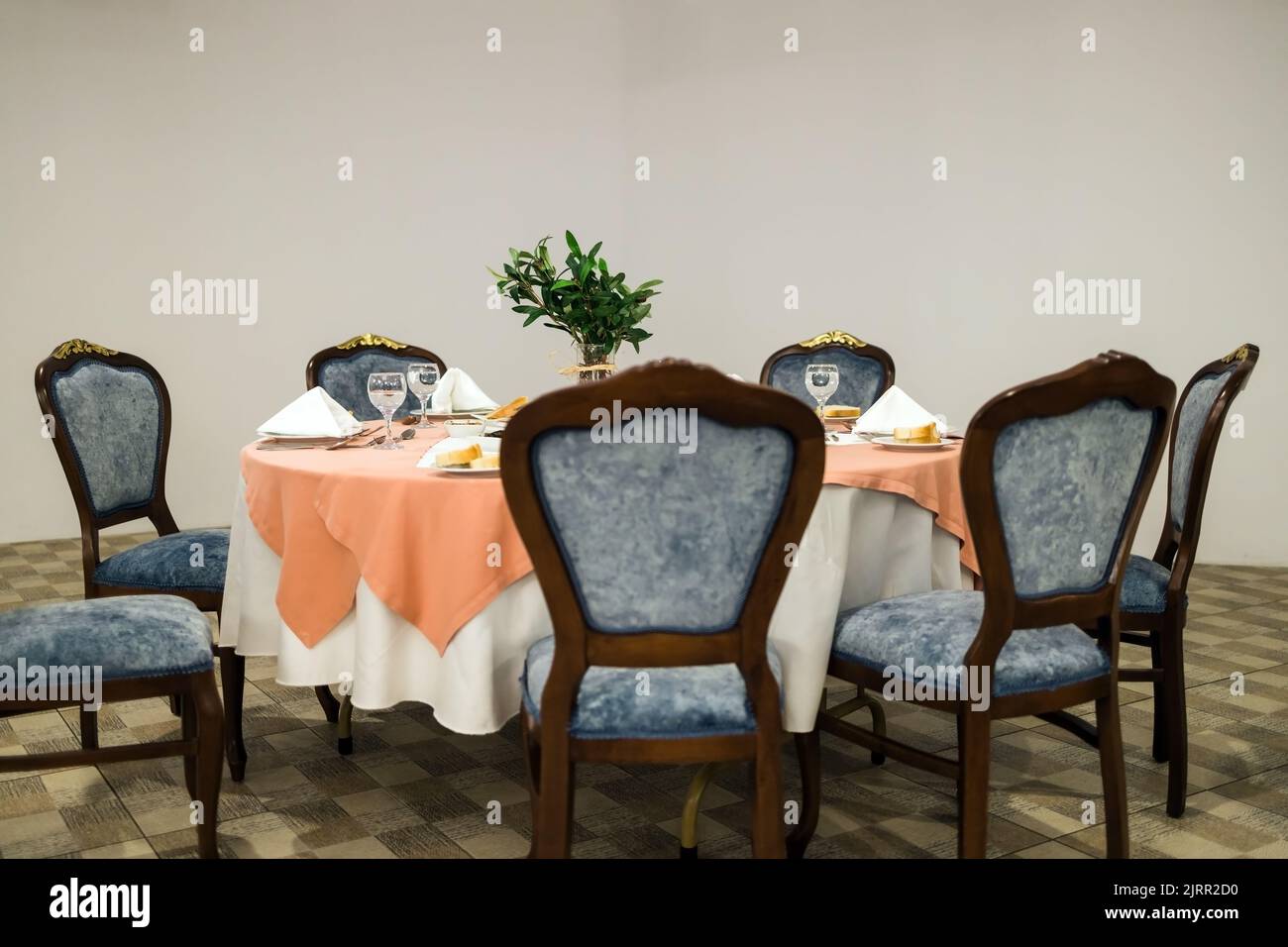 Sitzanordnung einer Hochzeit mit einem runden Hochzeitstisch in der Mitte eines kolonialen Speisesaals mit weißen, durchsichtigen Deckenvorhängen. Stockfoto